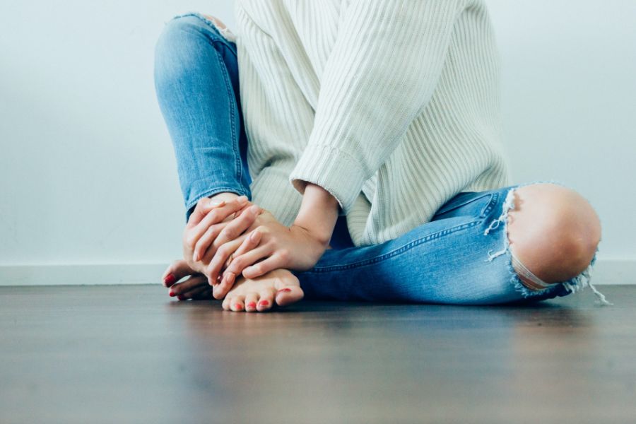 woman sitting on floor wearing distressed denim jeans